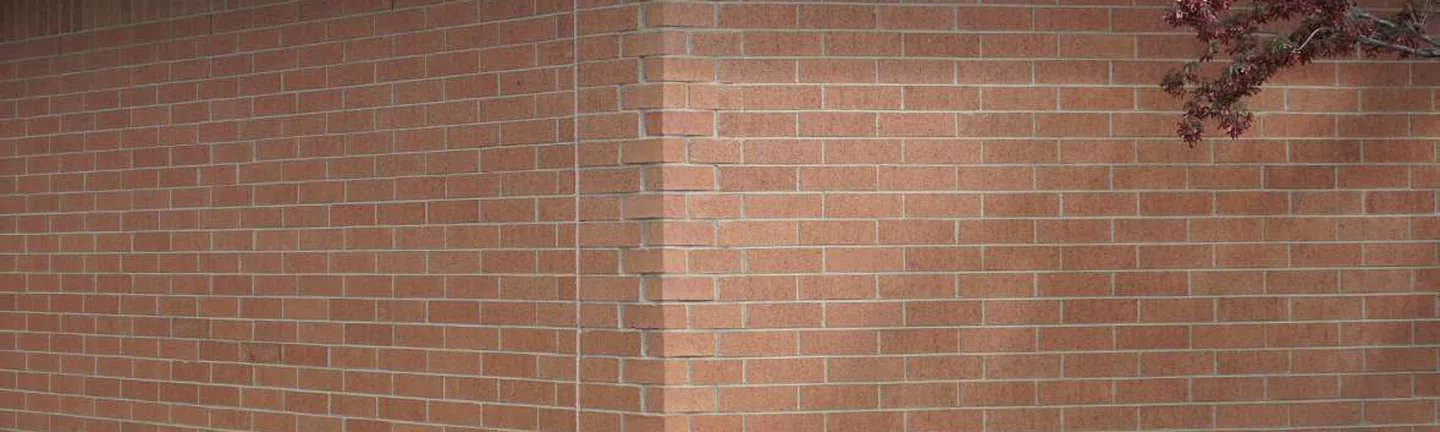 Red brick running through the shaped units at the outside corner of the Michigan building in 2019, the corner reading in the same range as both walls
