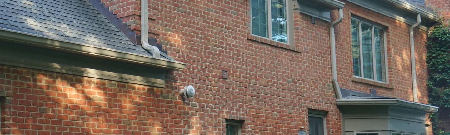 The side of the Michigan house in 2019, an even red brown brick range in evening sun under a stepped brick rake