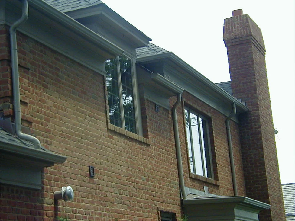 The gable end of the house in 2000, pale salmon runs of brick standing out in bands across the darker red wall, with a tall leaded window and a chimney beyond
