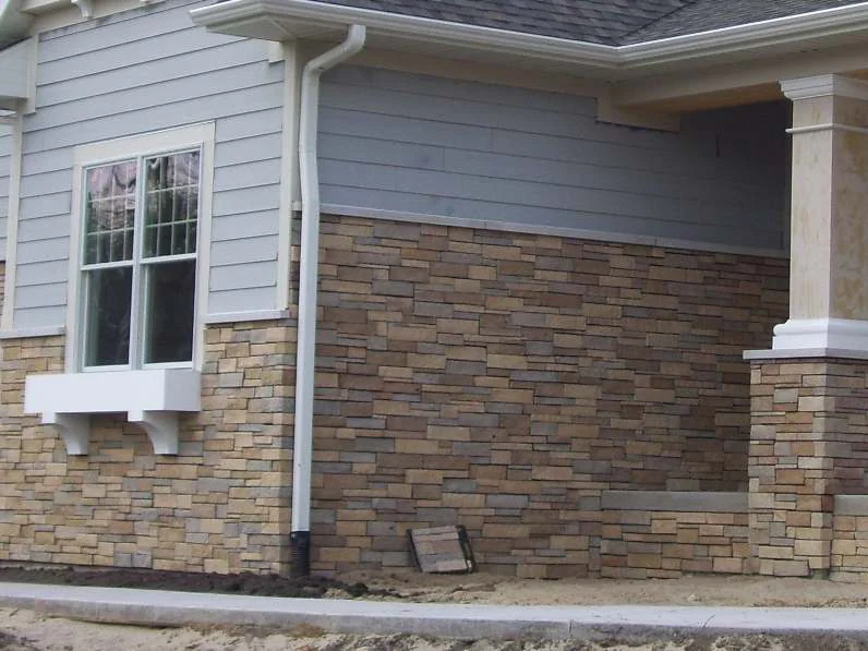 The same side wall in 2012 after staining, the stone veneer under the window box now reading as one tan and grey blend, bare soil and a new walk in front