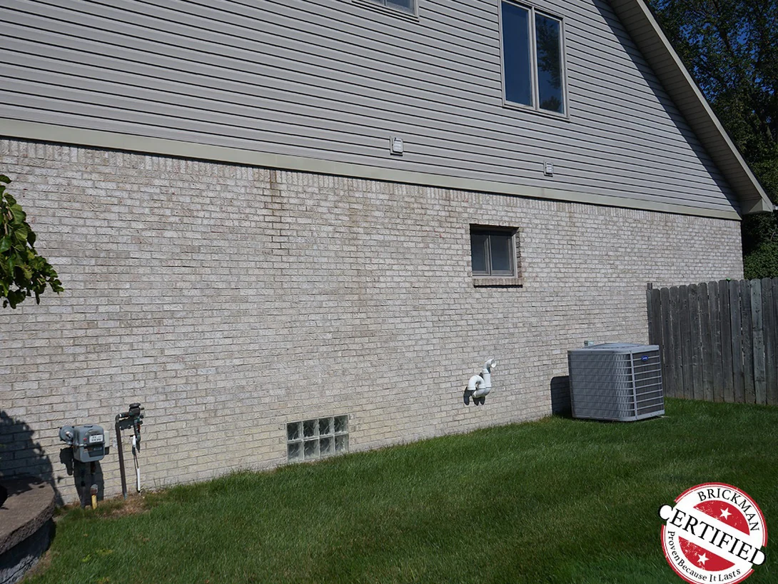 The same side elevation twenty-one years later, the brick reading as one even range under the siding and the long sweeping roof
