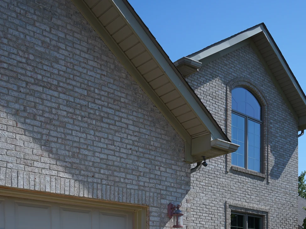 The front of the house in 2019, the brick reading as one range from the garage gable across to the arched window in the projecting bay.