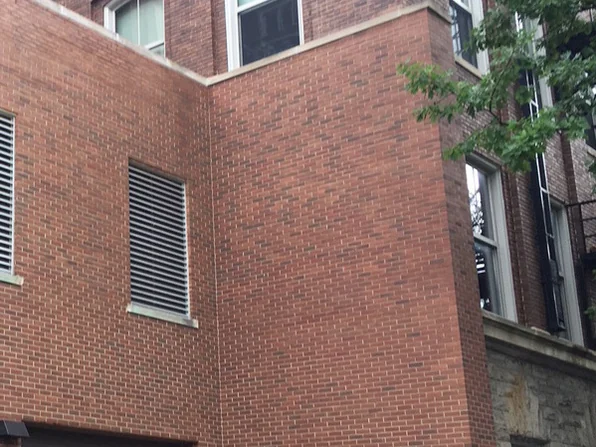 The same outside corner in 2019, the brick reading as one darker red range across both faces beside the louvered vent