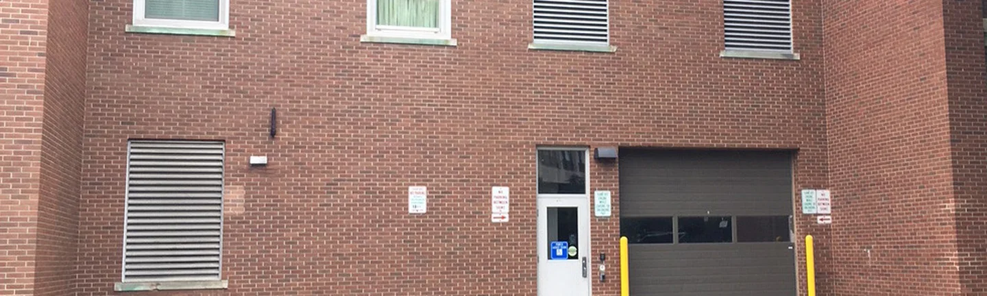 The rear elevation of the Michigan university building in 2019, windows and louvered vents set in one range of red brick