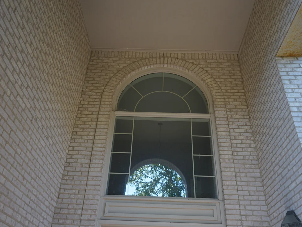The arched window above the front door seen from inside the entry porch, the white brick jambs and the arch ring turning with it