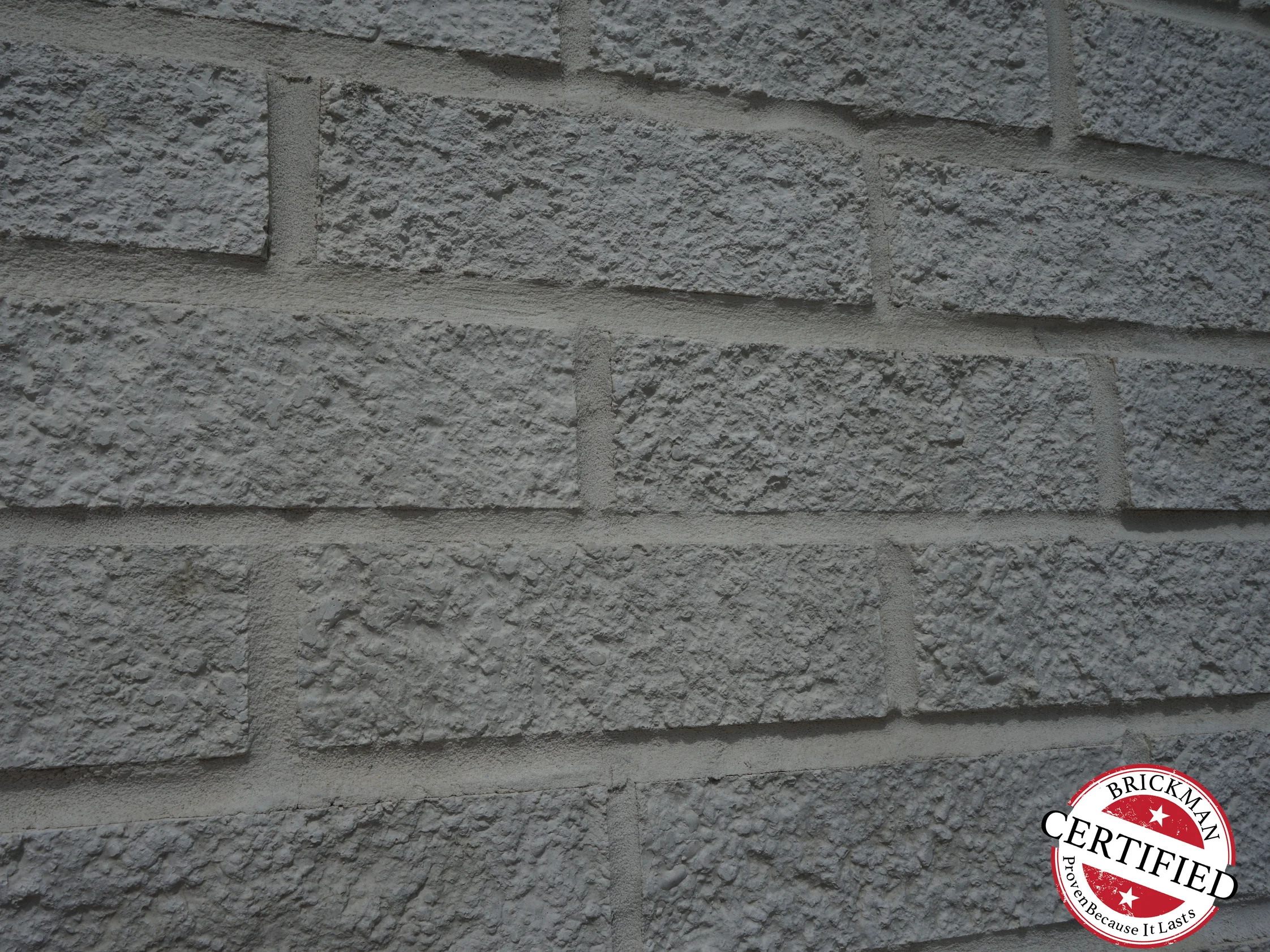 Close view of the white brick at unit scale in 2019, the mortar joints holding their white against the textured faces