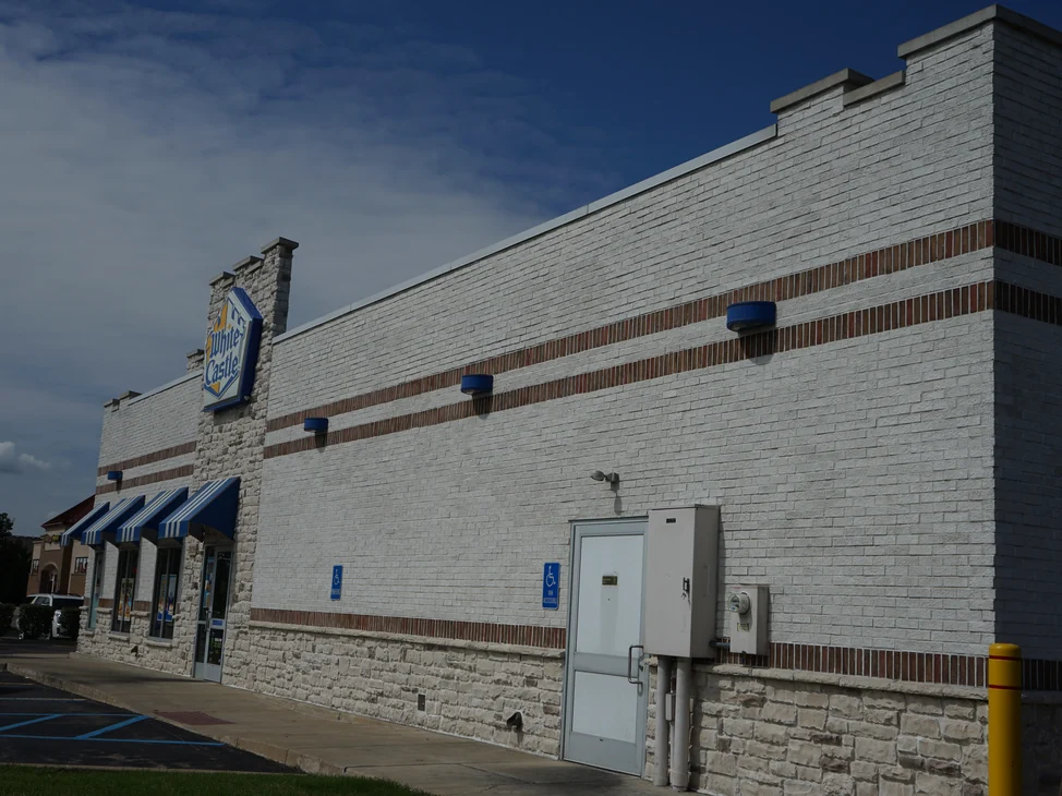 The White Castle elevation in 2019, its white brick and white mortar joints reading as one wall from the entrance to the far corner.