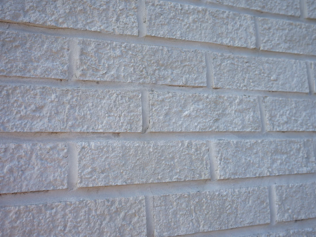 White brick photographed along the wall in 2019, the mortar joints between the courses the same white as the units