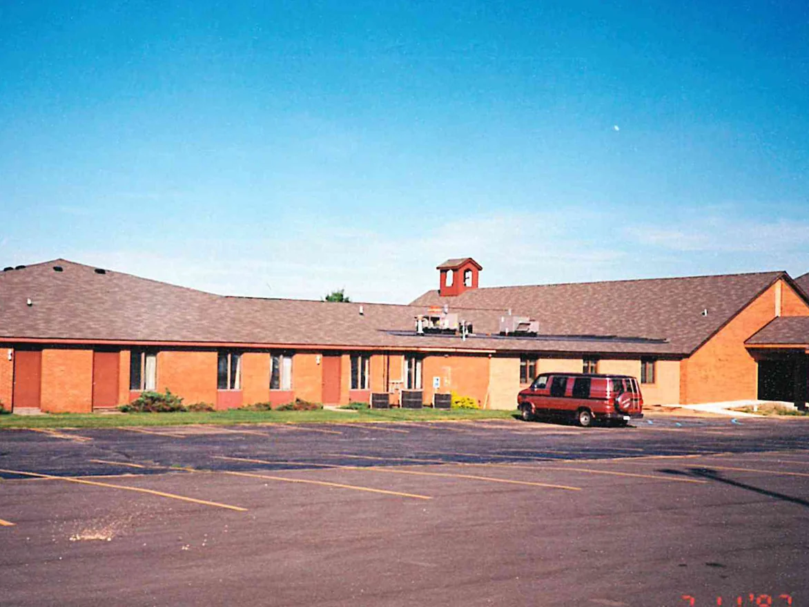 The church wing from the parking lot before staining, its brick a bright orange red with darker red panels set between the windows