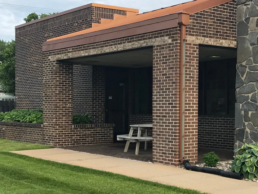 The covered entrance walk in 2019, a brick column running from the paving to the copper fascia