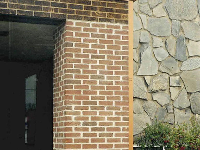 Close view of the added column in 2000, its brick light pink and cream beside the grey fieldstone wall