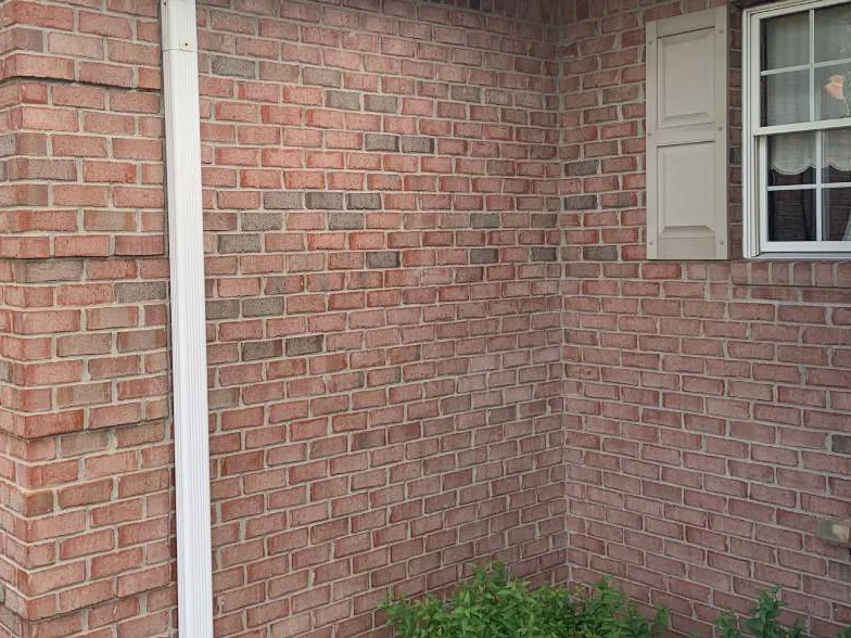 The same inside corner in 2019, both walls reading as one salmon range from the downspout to the shuttered window