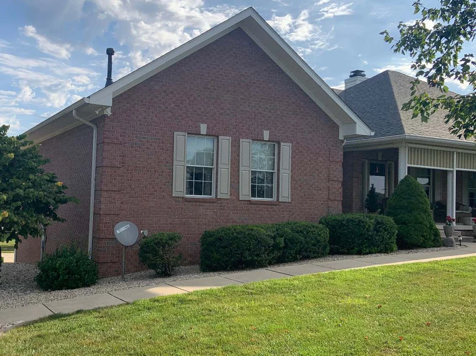 The gable end of a single-story brick home in 2019, its walls one even salmon range above a mown lawn