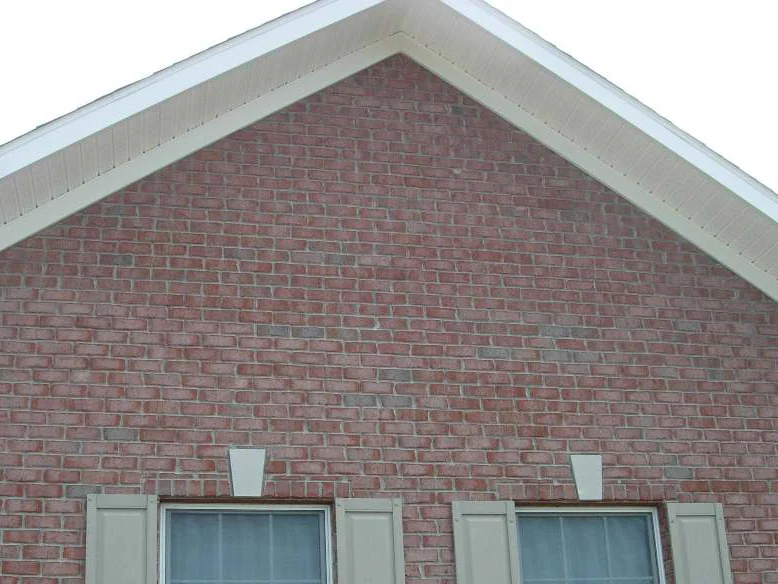The gable peak over two shuttered windows in 2007, the brick dark red with grey and darker units scattered unevenly through the courses