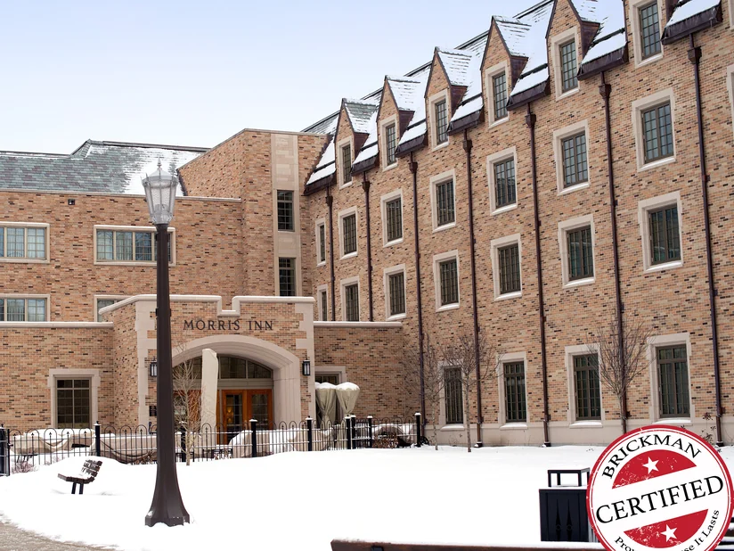 The inn entrance in 2019 across a snow-covered forecourt, its brick reading as one warm buff, tan and brown range up to the dormers.