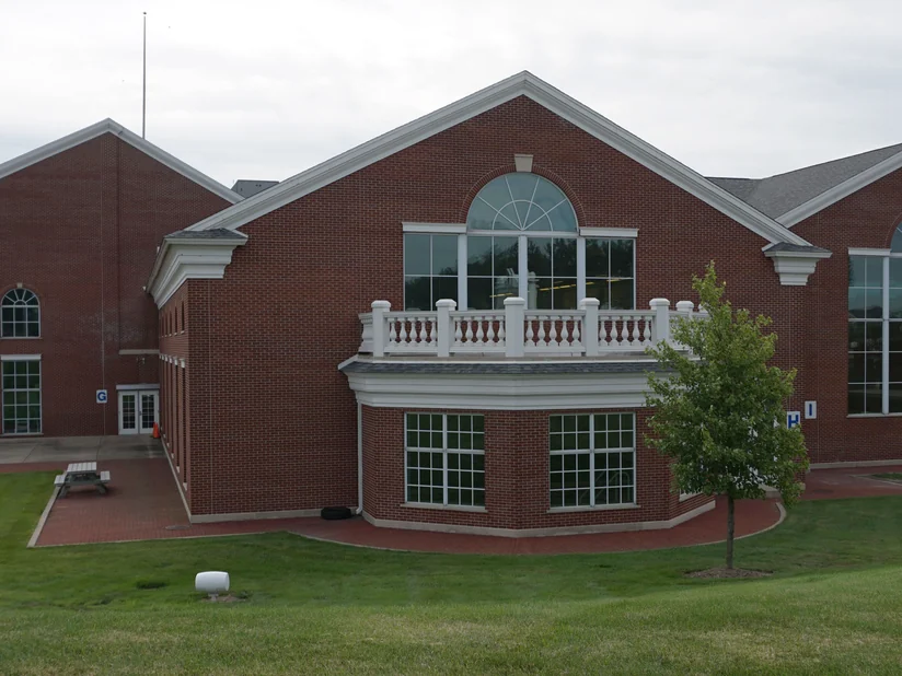 The hospital in 2019, a gabled brick pavilion with a balustraded balcony over a bay window, the brick holding one red range across every gable.