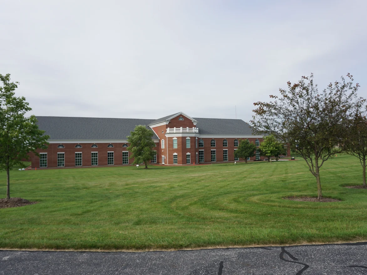 The hospital seen across its lawn in 2019, a long two-storey brick elevation with a pedimented centre bay, the brick even in color end to end