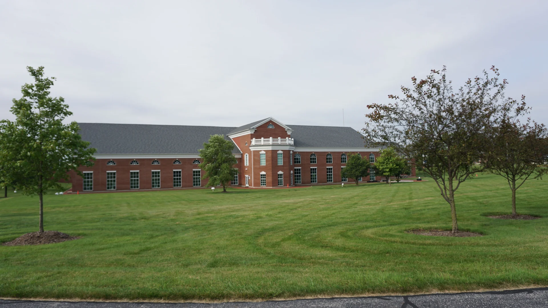 Munster Community Hospital across a wide lawn in 2019, its red brick one even range twenty-one years after staining