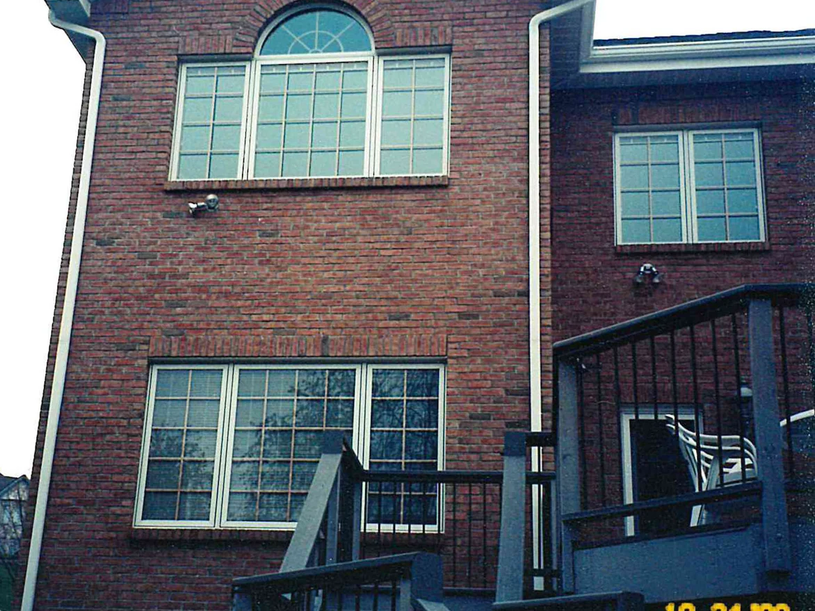 The rear of the house beside its deck stair in October 2000 with the work finished, the brick an even dark red across the wall and the gable