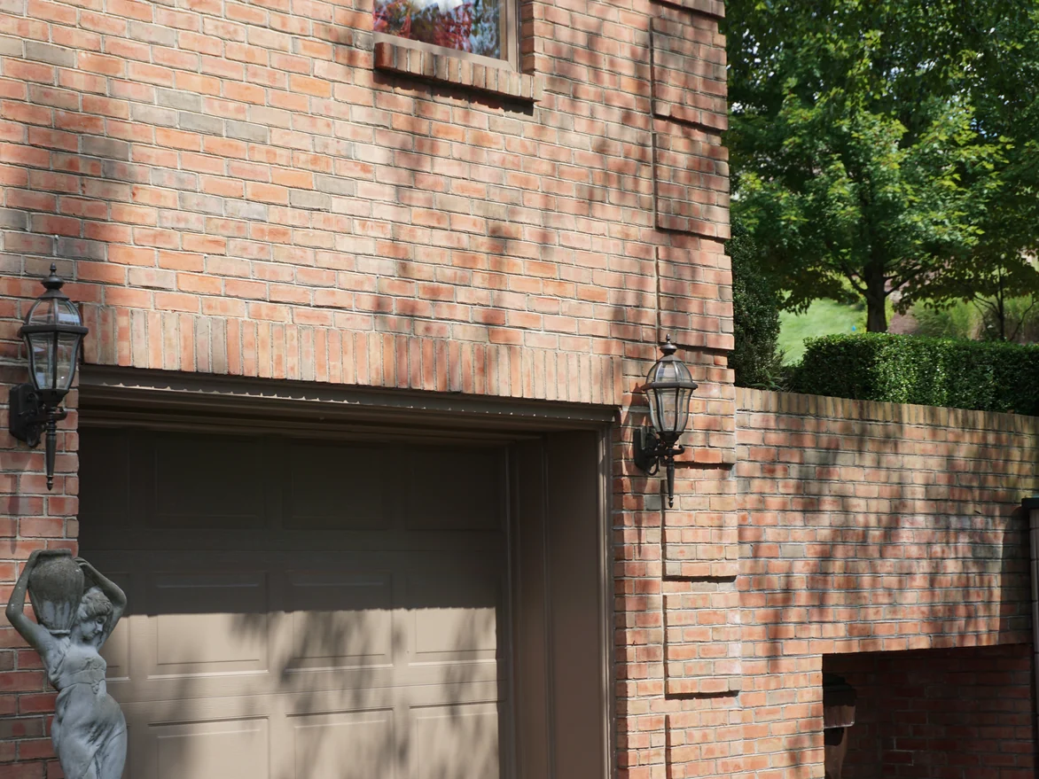 A garage bay and the low brick garden wall running away from it in 2019, both reading as the same orange and buff mix