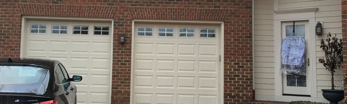 The garage of the New Albany house in 2021, the jack arch over each of the two white doors reading in the same dark red blend as the wall around it
