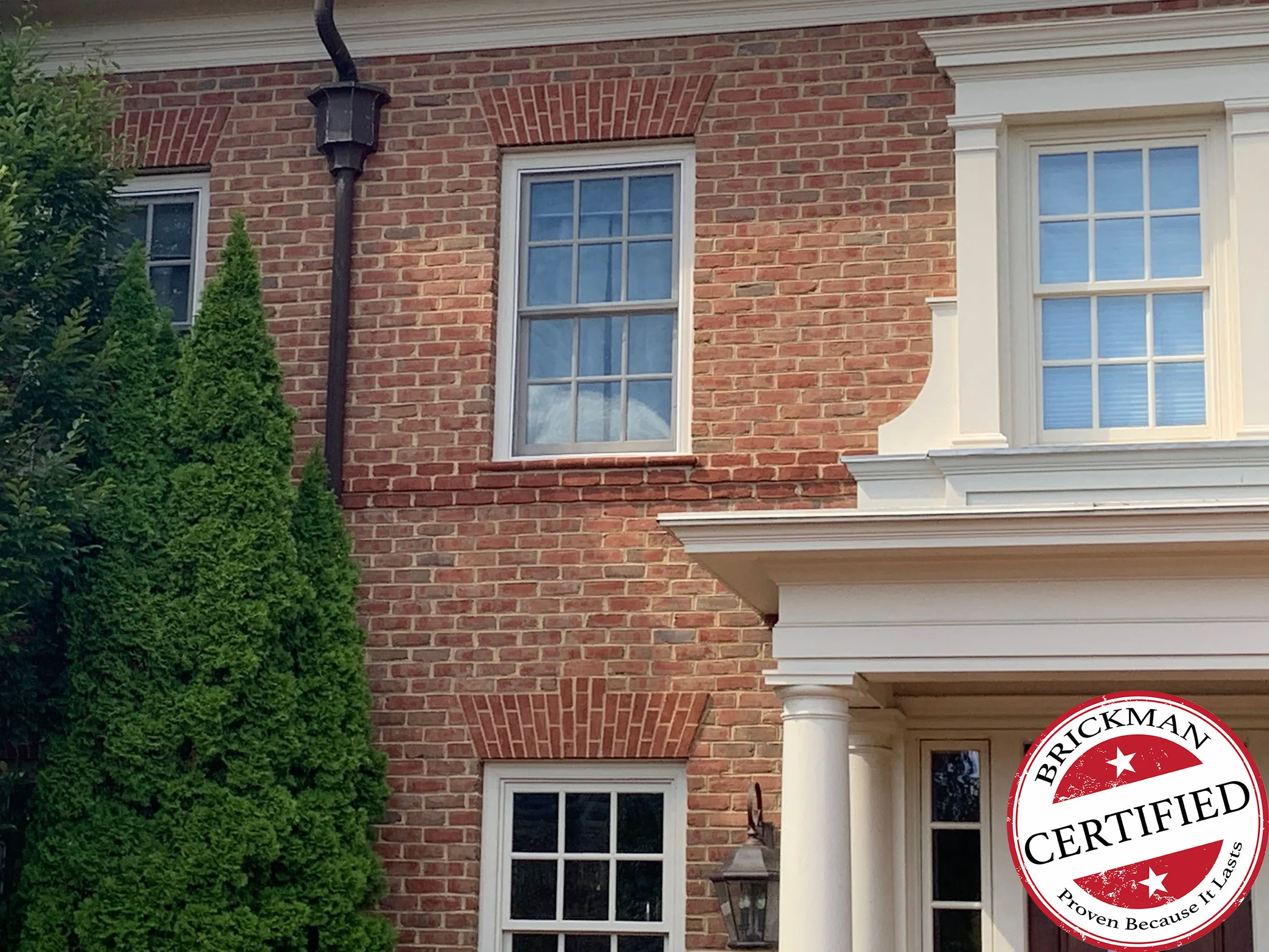 The right-hand bay of the house in 2019, jack arches over the upper and lower windows with the certification stamp in the corner
