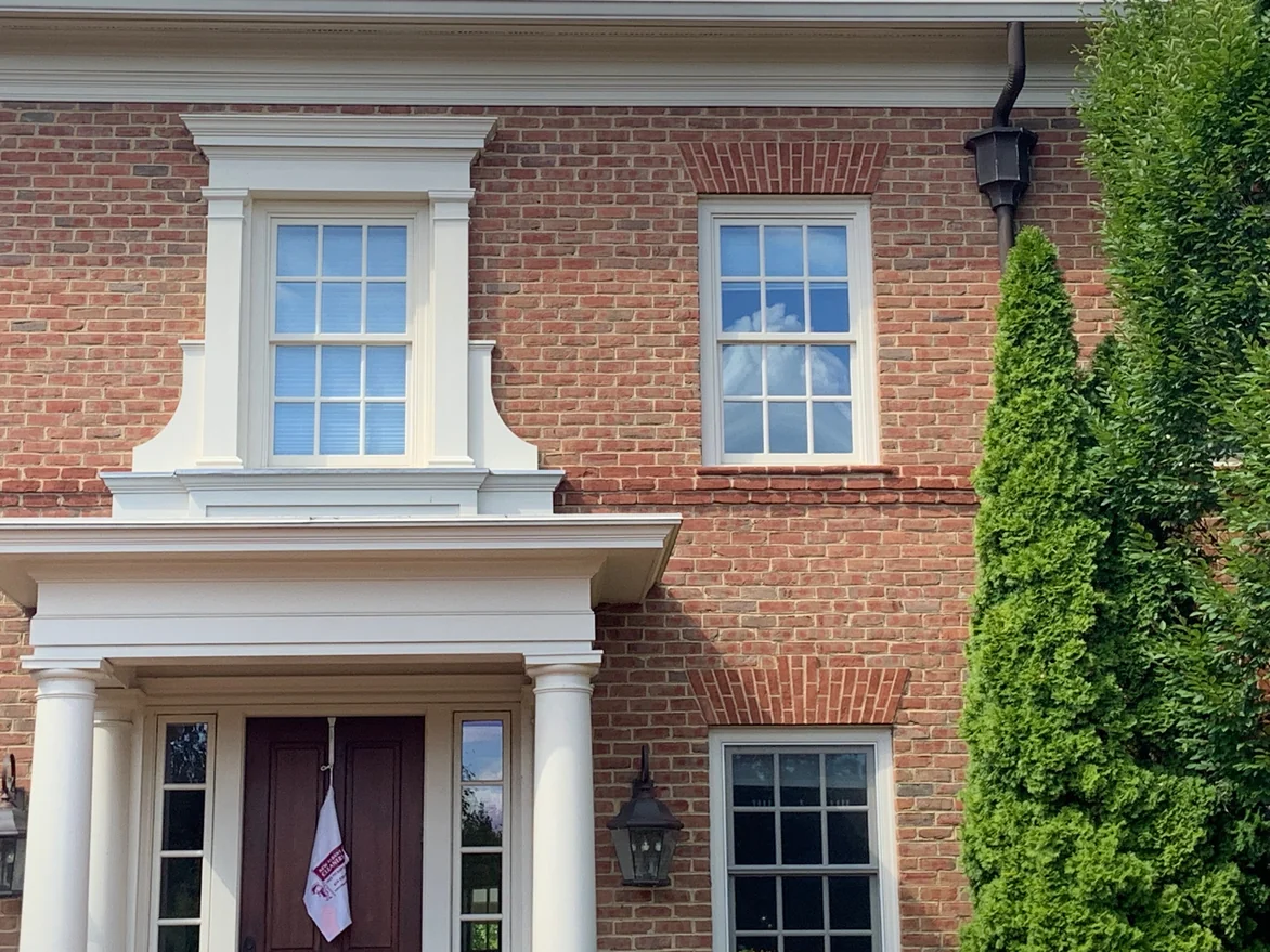 The center bay in 2019, a pedimented window surround above the entry porch with jack arches over the windows on either side
