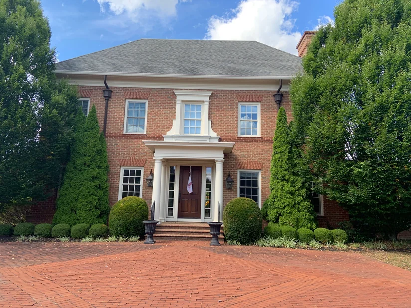 The front of the two-story brick house in 2019, jack arches over every window on both floors and a columned entry porch at the center.