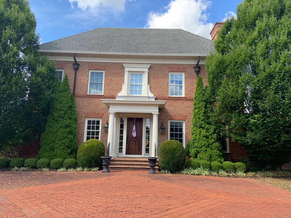 The front of the two-story brick house in 2019, jack arches over every window on both floors and a columned entry porch at the center.