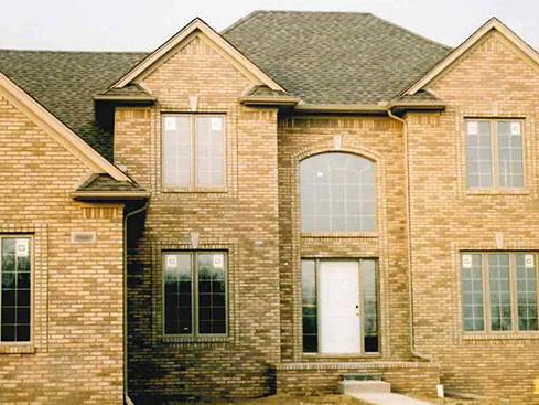 The same front three days later, the brick reading as one warm tan range across all three gables, the front door still in white primer