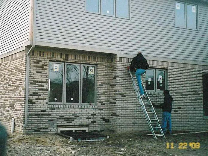 Two applicators at the rear wall on 22 November 2003, one on an extension ladder working stain into the dark units by hand and one at the foot of the wall