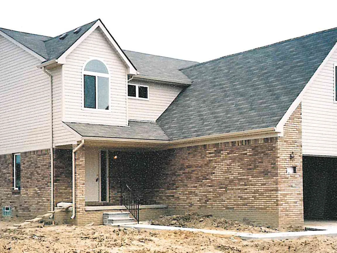 The house in June 2003 with the yard still bare dirt, its brick a mixture of cream and darker brown units under cream siding