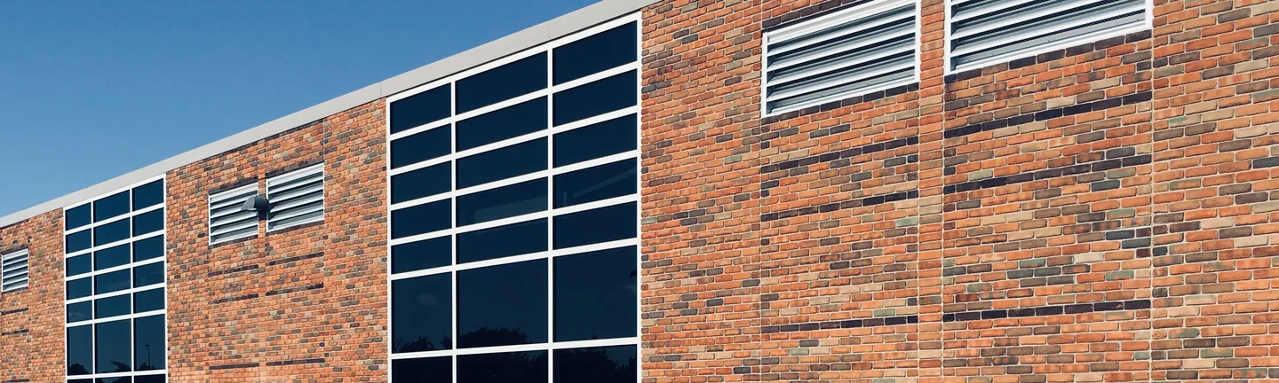 The long brick side of a Michigan high school in 2019, reading as one range from end to end