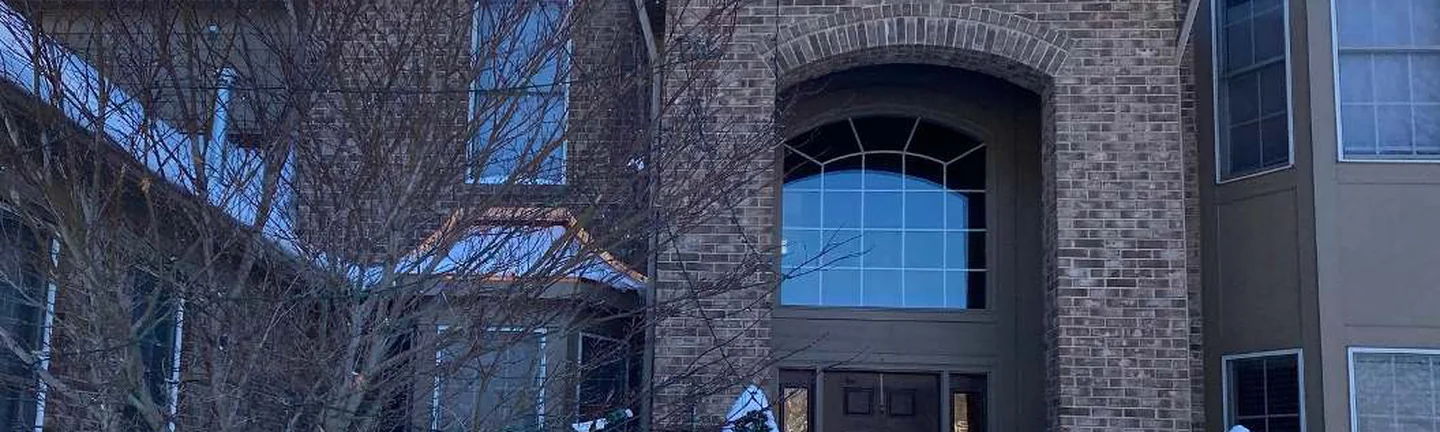 The front of the Northville house in 2021, brown brick reading as one range across the arched entry
