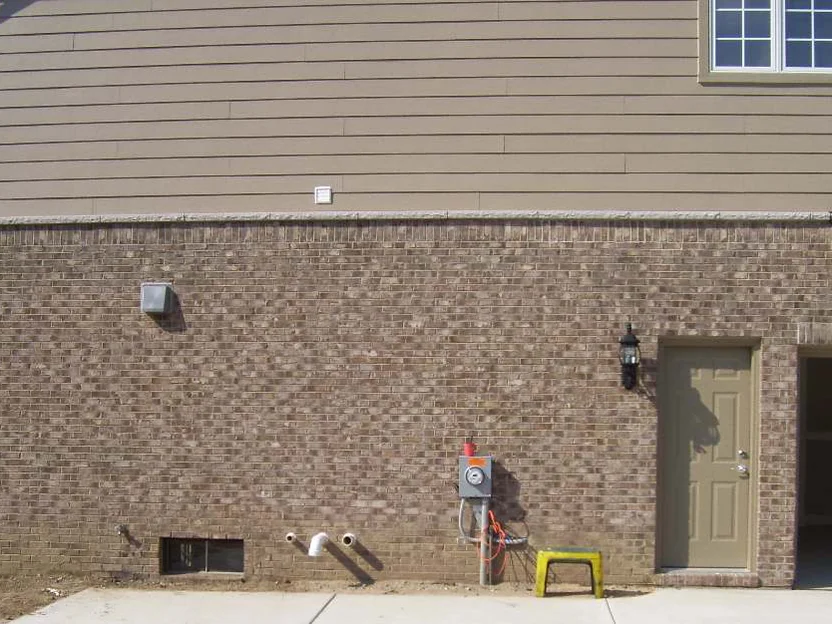 The garage side wall after staining in 2007, the light and dark blotches carried into one range, the drive poured and the service door hung