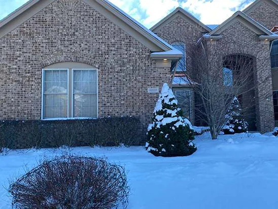 The house from the front lawn in 2021 in deep snow, the gable and the entry bay reading as one brick colour under a winter sky