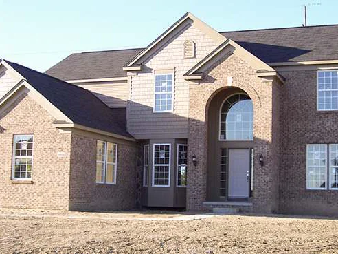 The same front elevation later in 2007, the brick reading as one tan range around the arched entry and the bay window, bare dirt still in front