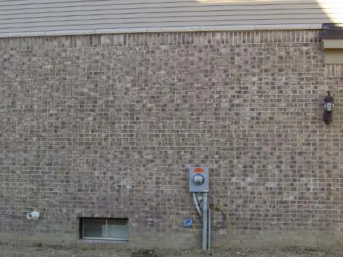 The garage side wall after staining in 2007, the courses reading as one range around the meter and the basement window