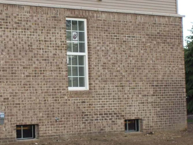 A side wall with one window in 2007, a block of lighter brick at the lower right beside two basement windows