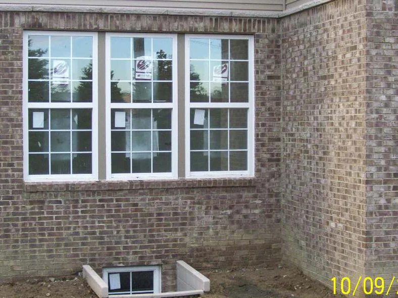 A triple window at an outside corner in 2007, the brick around it mottled with lighter patches, with a camera date of 10/09/2007