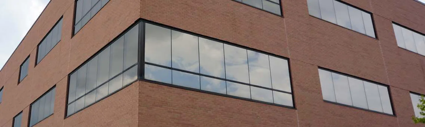 The corner of the Northville office in 2019, three floors of red brick and ribbon windows under an overcast sky