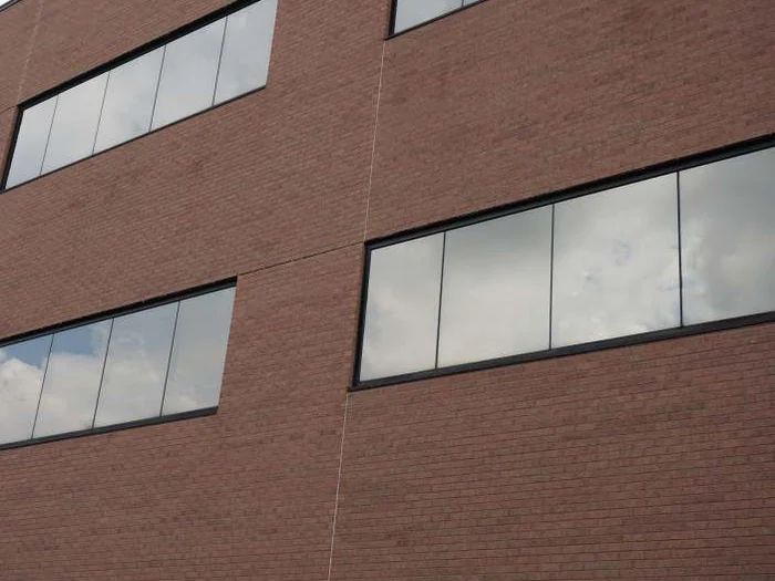 The upper wall in 2019 at the same vertical expansion joint between two ribbon windows, the header brick beside it reading as one range with the field around it