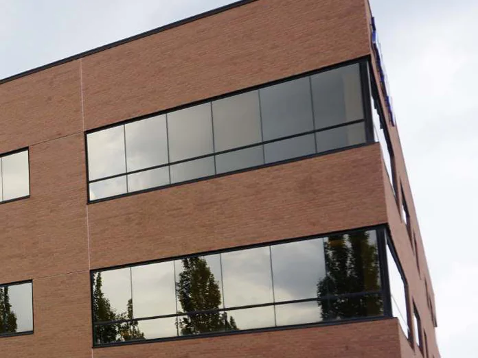 The top corner of the office in 2019, red brick around the corner window and up to the parapet cap, the same corner the lift was working in 1999