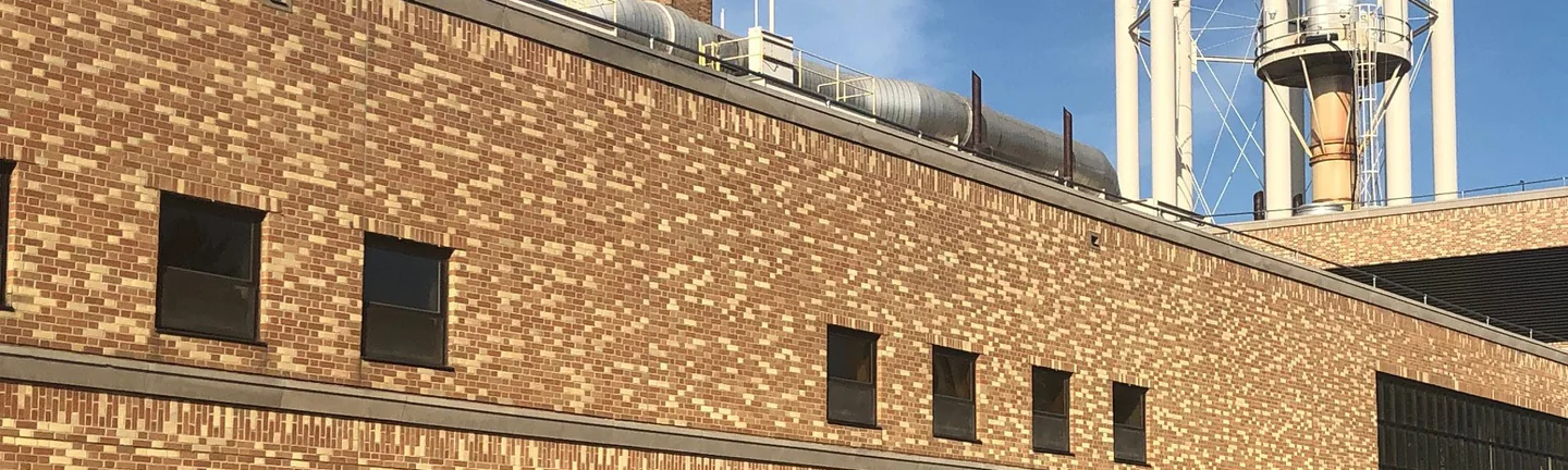 The long brick elevation of the Notre Dame power plant in 2019, its stack and water tower behind