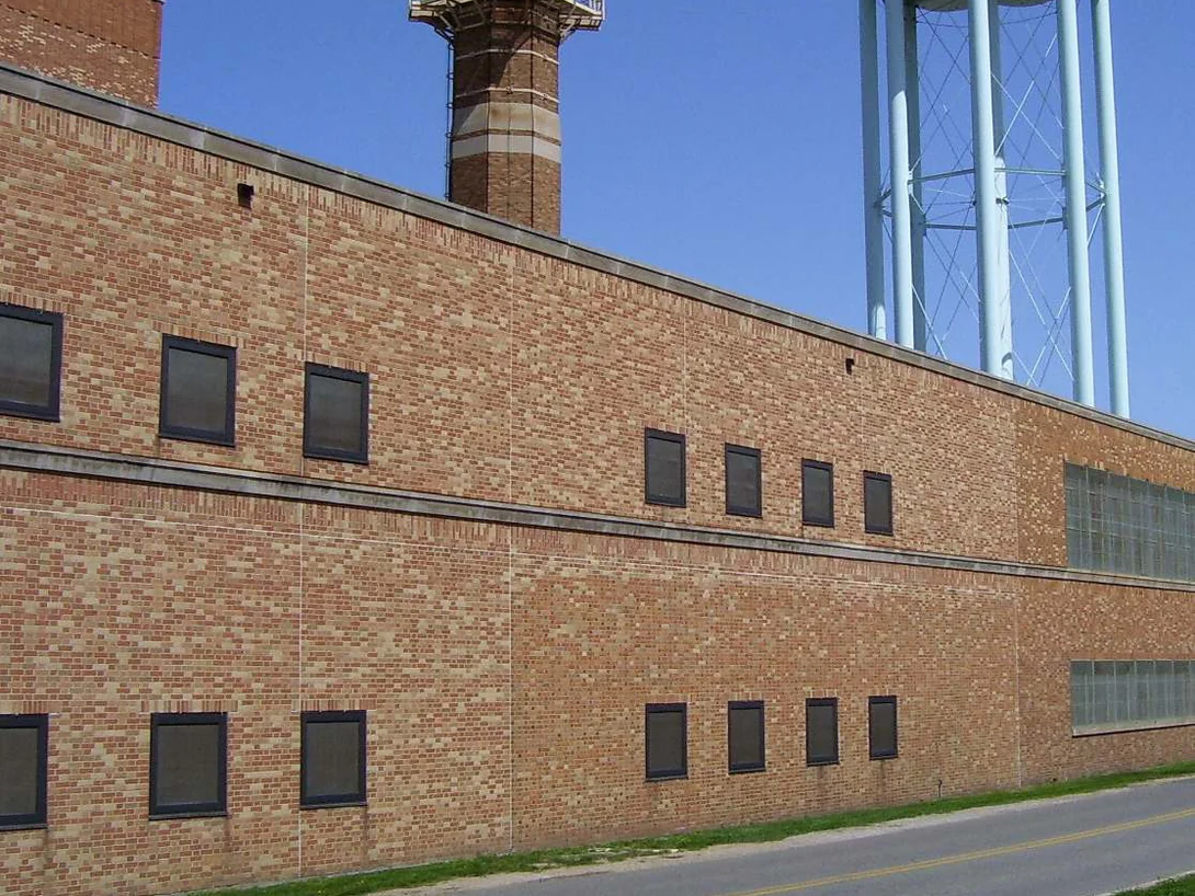 The power plant elevation in 2008, its brickwork running in bands of noticeably different colors, with the stack and water tower behind