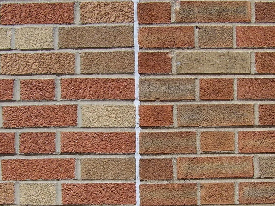 Brick at close range, two runs of different texture meeting at a mortar joint and carrying the same color