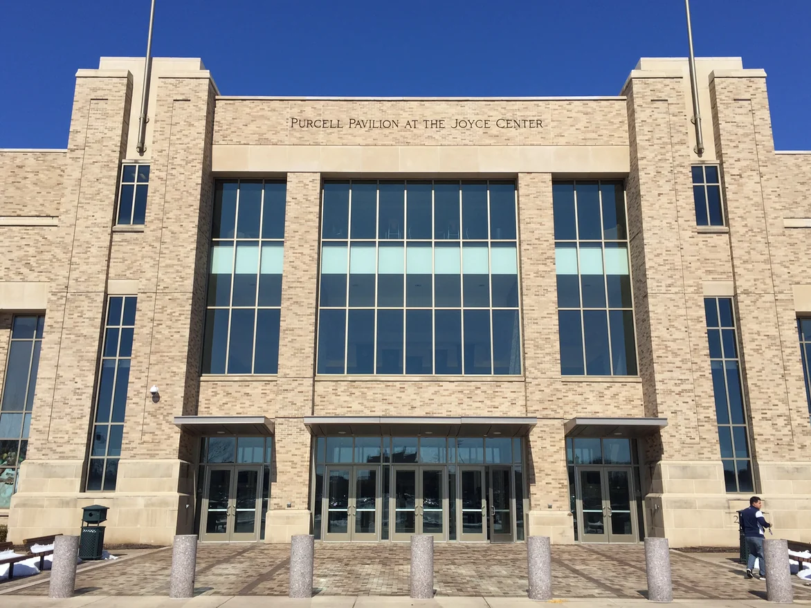 The entrance front of Purcell Pavilion at the Joyce Center, its buff brick carrying darker units scattered evenly across the whole elevation