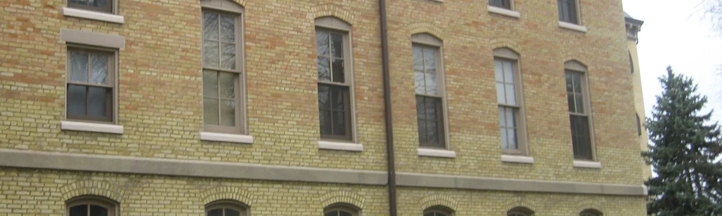 The long side wall of Washington Hall before the work, the upper two floors reading orange and pink against the pale yellow brick below
