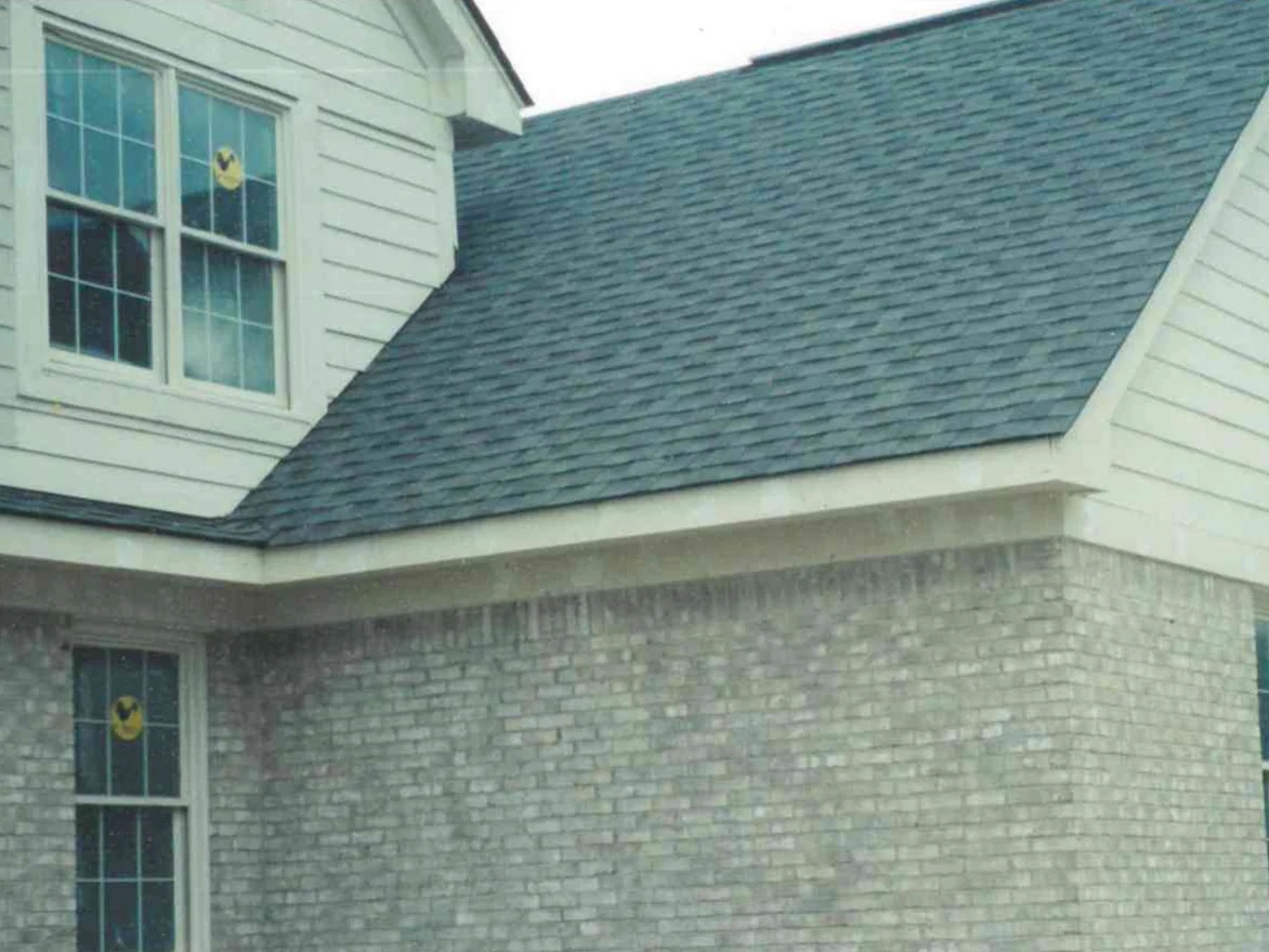 The same corner of the house in July 1999 after the damaged areas were stained, the brick reading as one grey range under the soldier course and the gable