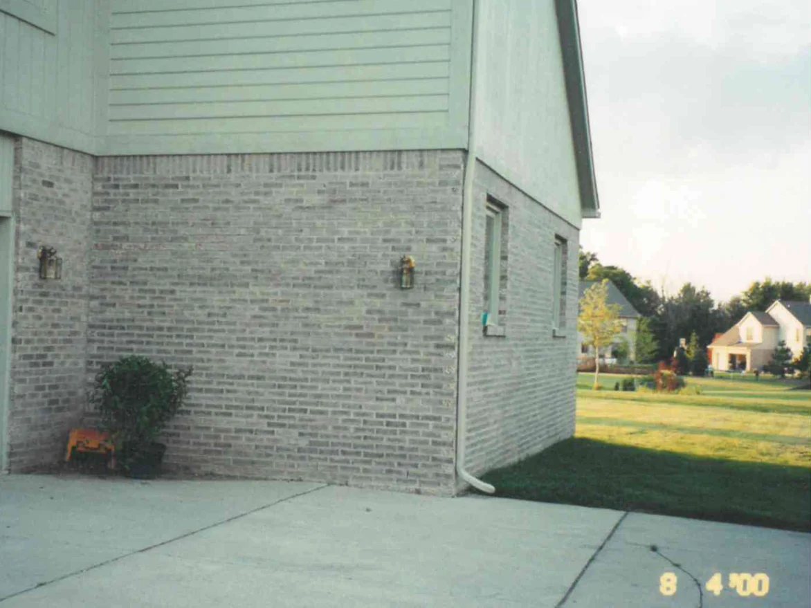 The same corner of the house on August 4, 2000, the brick reading as one grey range under the soldier course, with a lantern either side of the wall and the camera date in the corner